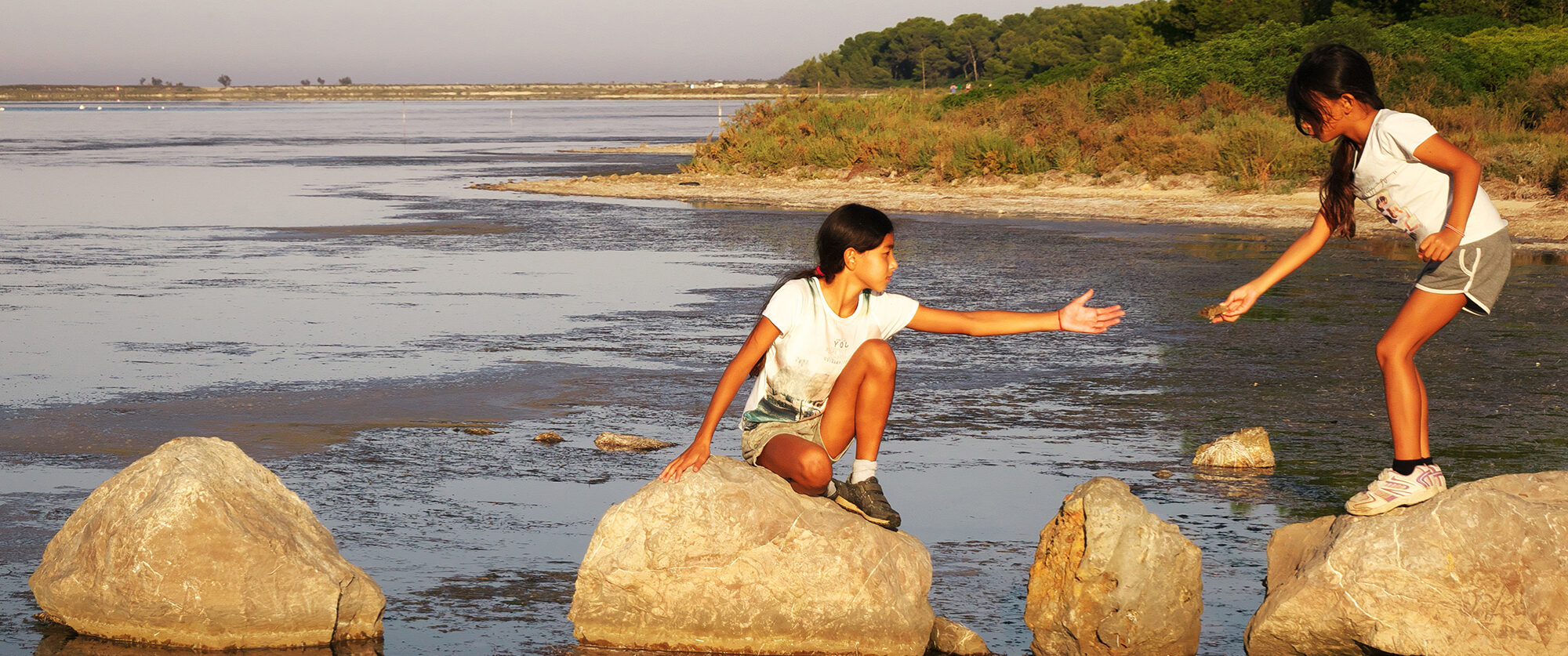 Little girls crossing the river over rocks